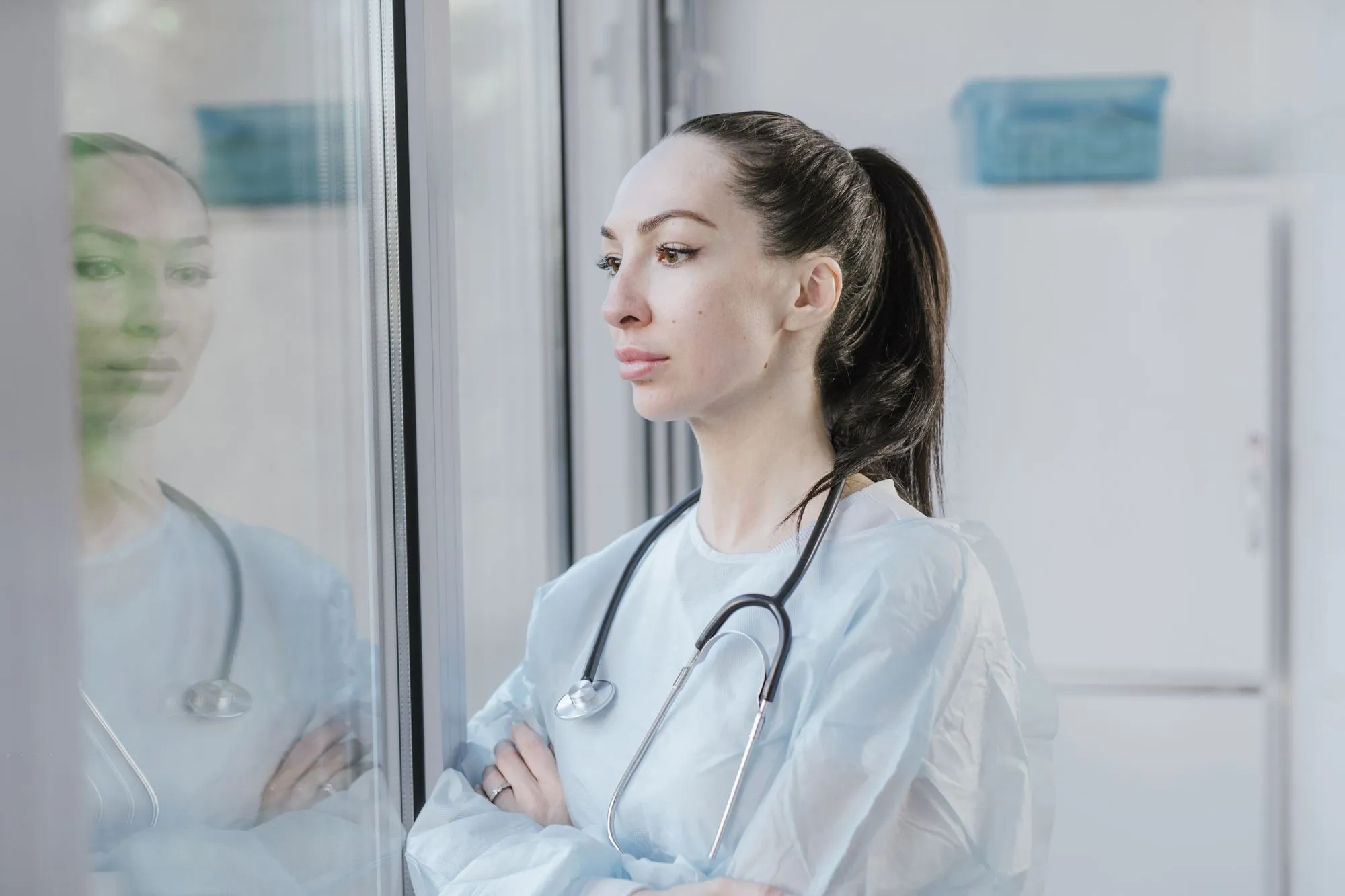 Médica pensativa junto a una ventana en su consultorio